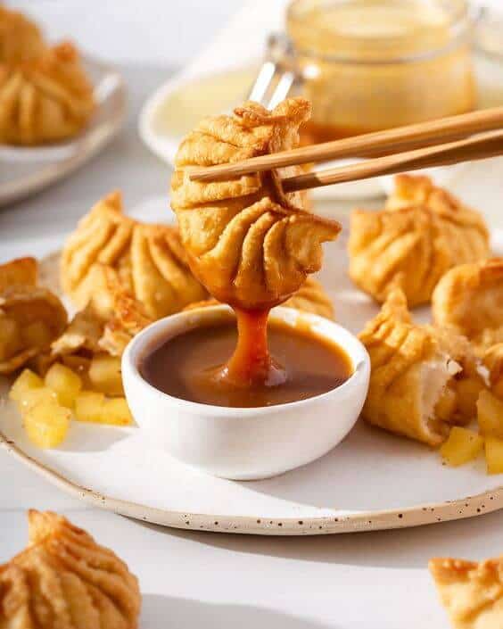 An apple pie dumpling dipping in miso-caramel sauce with chopsticks