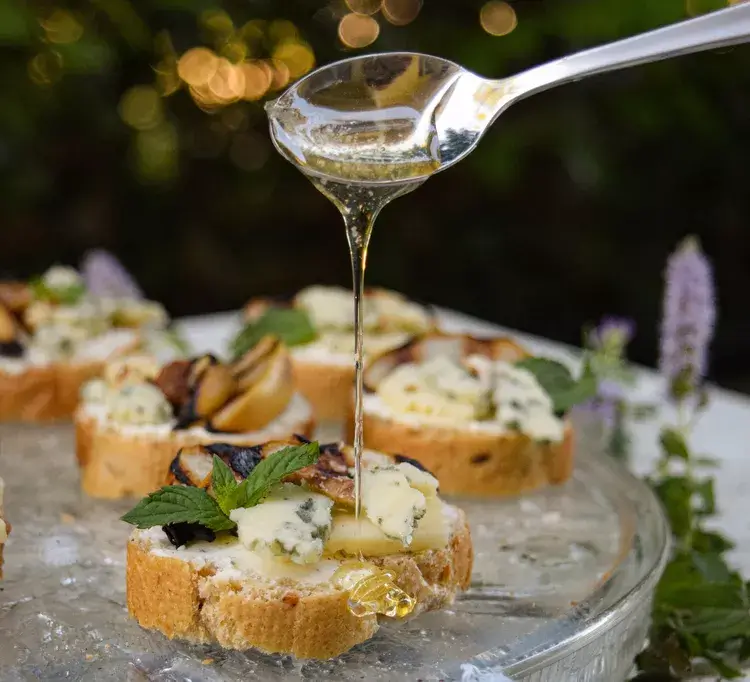 Crostinis with blue cheese, pears, and a spoon drizzling honey
