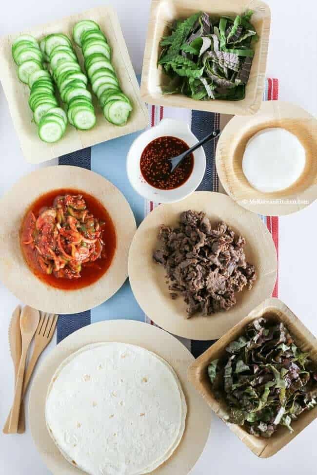 Beef bulgogi taco bar with all of the ingredients in bowls