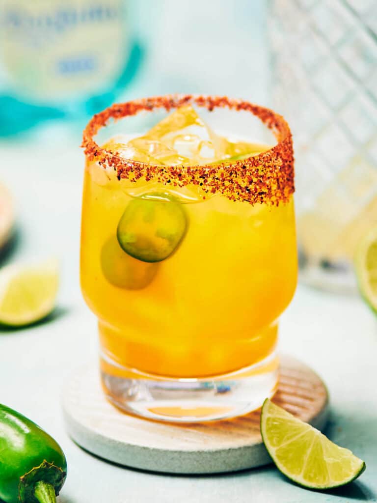 Spicy mango margarita with tajin rim and jalapeno garnish