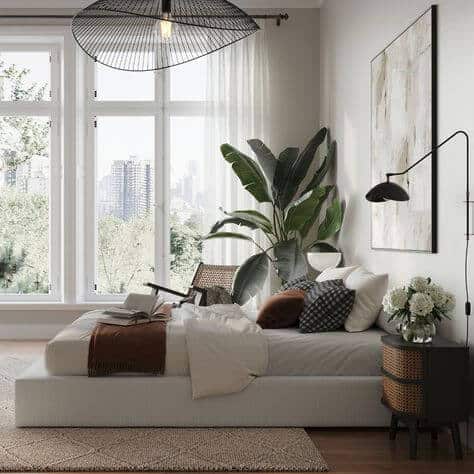 A light and airy masculine bedroom that uses natural light and a large plant to add elements of the outdoors to the space.