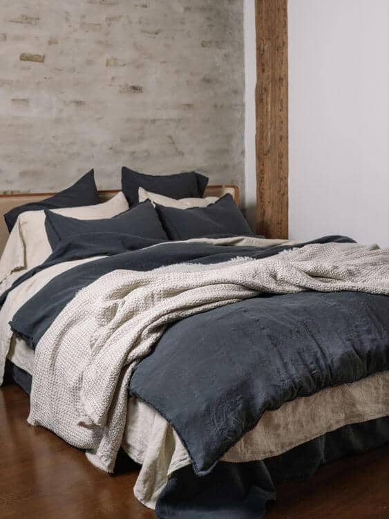 Layered navy and oatmeal bedding for a masculine look with a neutral edge