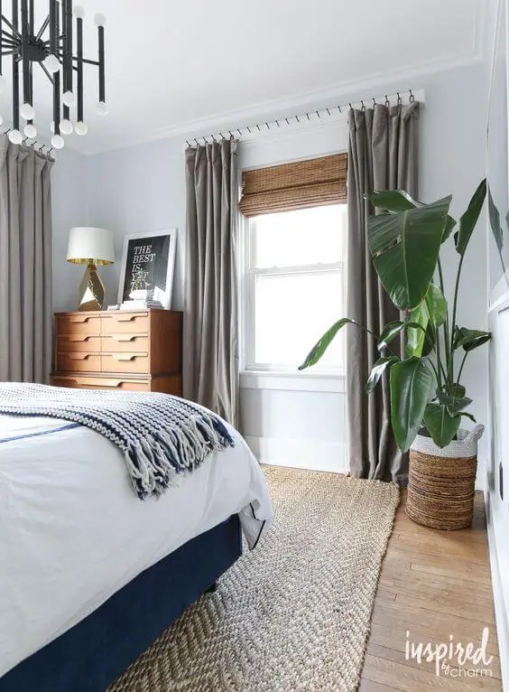 Floor to ceiling curtainns in a neutral grey color compliment this space well. They lean into a masculine feel with additional warmth from the carpet and wooden accents.