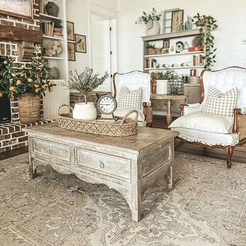 Antique furniture in a white farmhouse living room, adding character and timeless charm to the space. The vintage pieces blend seamlessly with the neutral palette and rustic decor, enhancing the farmhouse aesthetic with a touch of history and warmth.