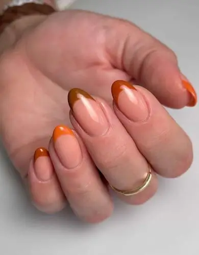 Close-up of burnt orange French tips for fall nails, featuring a modern twist on a classic manicure with warm, autumnal tones, perfect for a trendy seasonal look.