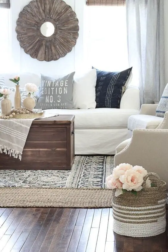 Layered rugs in a farmhouse living room, combining a neutral jute base with a patterned top rug, adding depth, texture, and warmth to the rustic space.