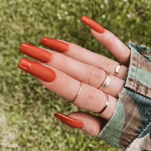 Close-up of matte fall orange nails, featuring a warm, vibrant shade perfect for an autumn manicure, ideal for those seeking a trendy and seasonal nail design.