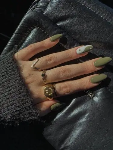 Close-up of olive green fall nails featuring a stylish yin yang design on the ring finger, combining earthy tones with a unique, trendy accent for a chic autumn manicure.