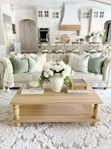 White farmhouse living room with soft pastel accents, featuring blush pink throw pillows and pale blue decor items that add warmth and charm to the neutral space