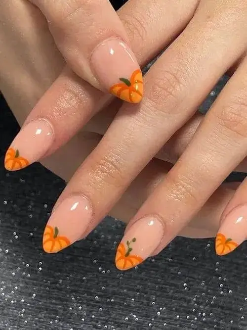 Pumpkin nails for fall, showcasing orange pumpkin designs with green vines on a neutral glossy base, ideal for a trendy and festive seasonal manicure.