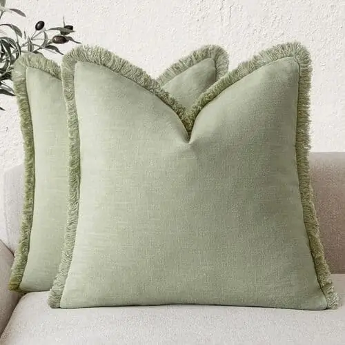 Sage green throw pillows in a white farmhouse living room, adding a subtle touch of color and enhancing the cozy, neutral decor with a hint of natural, calming green.