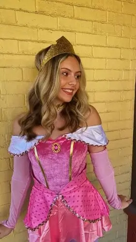 Sleeping Beauty costume idea featuring a classic pink gown with a fitted bodice and flowing skirt, paired with a gold crown and elegant choker, perfect for a dreamy and enchanting Halloween or cosplay look inspired by Princess Aurora.