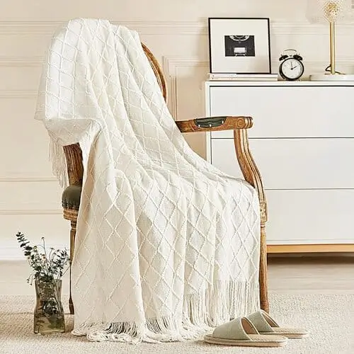 Cozy farmhouse throw blanket draped over a sofa in a rustic living room, featuring soft, textured fabric that adds warmth and charm to the space. Perfect for enhancing the farmhouse decor and creating a welcoming, comfortable atmosphere