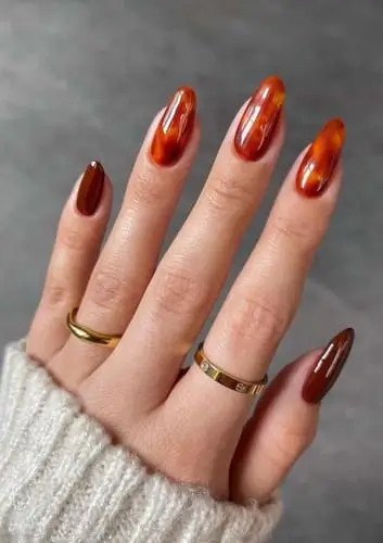 Close-up of trendy tortoiseshell nails featuring a blend of warm amber and rich brown tones in a marbled pattern, creating a sophisticated and stylish fall manicure.