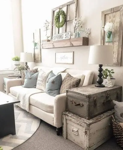 Vintage trunk repurposed as a coffee table in a white farmhouse living room, adding rustic charm and functional storage. The weathered wood finish complements the farmhouse decor, making it a stylish and practical focal point.