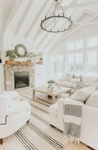 Bright and airy white farmhouse living room featuring soft neutral tones, cozy throw blankets, and wooden furniture, creating a warm and inviting space with a modern farmhouse style.