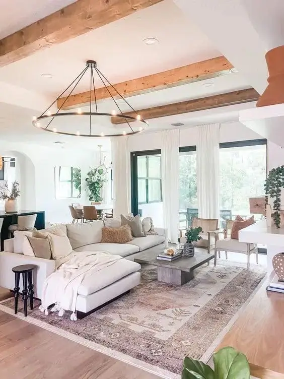 White farmhouse living room featuring exposed wooden beams, shiplap walls, and neutral decor, creating a cozy and rustic atmosphere with modern farmhouse charm.