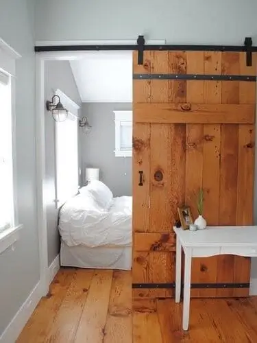 Rustic barn doors dividing living room and bedroom in a modern combo space – discover creative room divider ideas for small spaces.