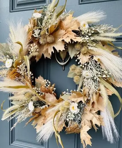 Boho fall wreath featuring earthy tones, dried flowers, feathers, and rustic pumpkins. Adds a warm, eclectic touch to your front door and autumn decor.