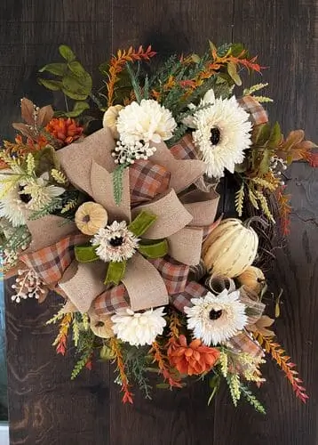 Rustic burlap wreath adorned with sunflowers, acorns, and wooden monogram, ideal for cozy fall decor. Perfect for farmhouse style or front door decoration.