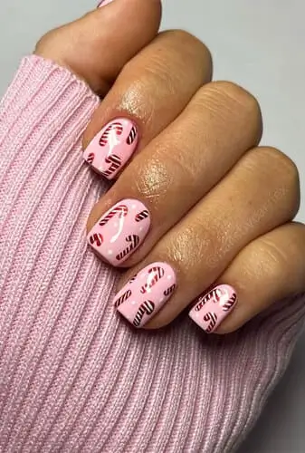 Pink nails with hand-painted candy cane design, festive holiday nail art idea with cute and playful Christmas vibes.