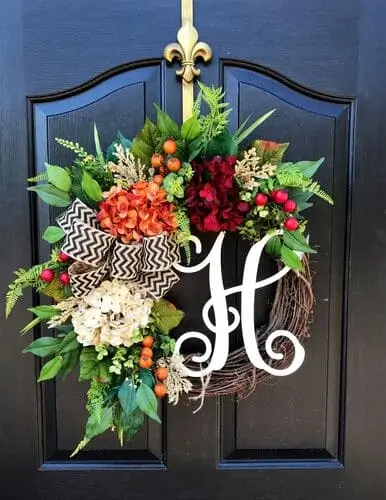 Monogram fall wreath featuring a personalized letter surrounded by autumn leaves, berries, and rustic accents. Perfect for customized seasonal decor on your front door.