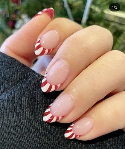 Festive peppermint French tip nails for Christmas 2024, featuring red and white candy cane stripes for a playful and stylish holiday manicure.