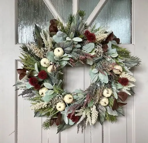 White pumpkin wreath with pops of burgundy flowers and greenery, creating an elegant fall decor piece for your front door or home. Perfect for autumn styling.