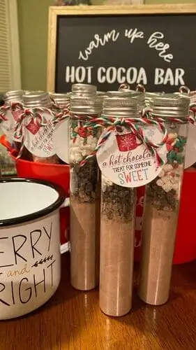 DIY hot chocolate party favors in little tubes, filled with cocoa mix, marshmallows, and festive toppings – perfect for holiday gifts and Christmas party favors.