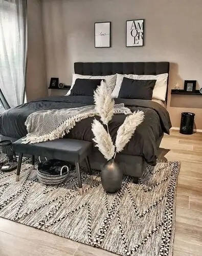 Neutral black, cream, and taupe bedroom with woven textured rug, pampas grass, and black and white wall art. Perfect for modern boho bedroom decor inspiration.