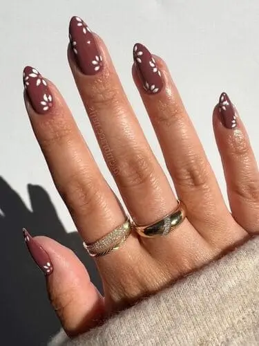 Elegant brown nails with dainty white flower accents—chic nail art inspiration for a soft, floral manicure look.