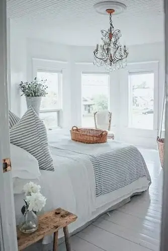 Coastal vintage bedroom featuring ticked striped bedding, perfect for adding a relaxed, beachy vibe to women’s bedroom ideas. Ideal for creating a charming, coastal retreat.