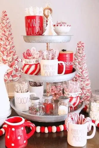 Holiday hot cocoa tiered tray with mugs, marshmallows, candy canes, and festive toppings – perfect for Christmas coffee bar or winter party decor.