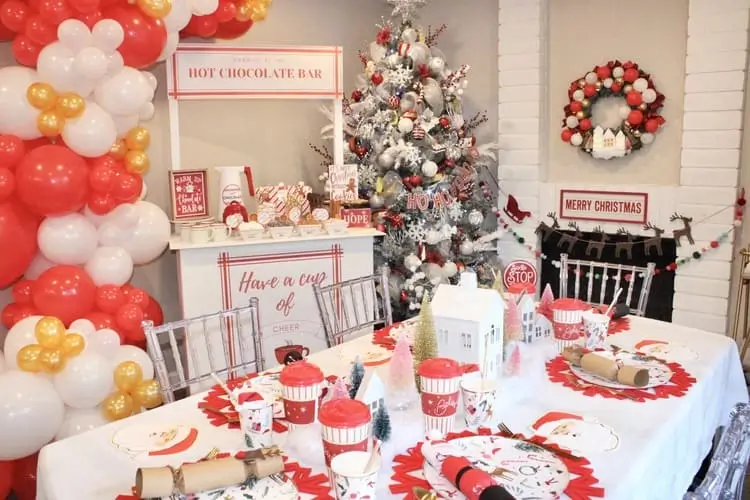 Kids' hot cocoa bar with red, white, and gold theme, featuring festive balloons and to-go cups for outdoor activities – perfect for winter parties and celebrations.