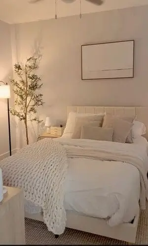 Serene white and oatmeal bedroom with an elegant olive tree, featuring soft neutral tones and natural elements for a calming, minimalist design.