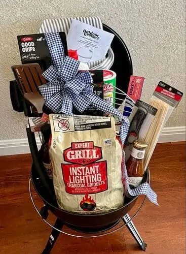 BBQ lover's gift basket for man's Christmas gift. Fill with BBQ essentials such as his favorite sauce, tongs, knives, grilling hand towel, skewers, and more.