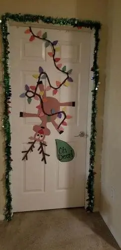 Christmas door decoration ideas: Rudolph the Red-Nosed Reindeer tangled in Christmas lights crafted from felt for a festive bedroom door design.