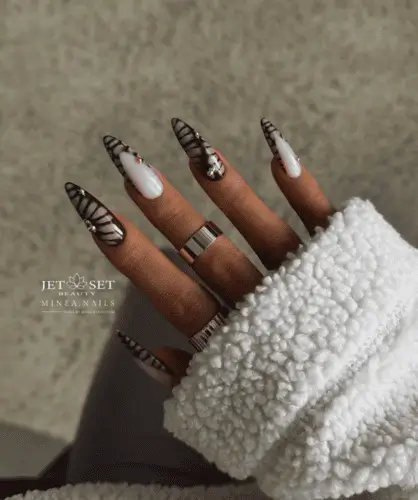 Elegant long almond nails with a mix of luxurious brown and neutral croc print, featuring gold charms for added glamour. Some nails are adorned with croc-style French tips, while others have a full crocodile print for a bold, trendy look.