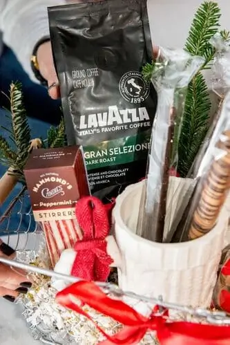 Coffee lover's Christmas basket with fresh coffee beans, biscottis, coffee mugs, peppermint stirrers, treats, coffee scoop, and more. You can easily DIY this coffee Christmas basket for men for a fraction of the price 