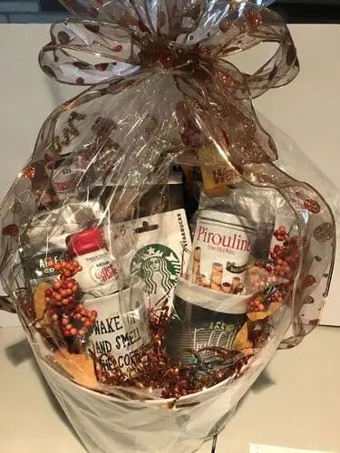 A coffee lover's basket perfect for men's Christmas gift basket full of essentials like seasonal festive syrups, light, medium, and dark roast coffee, biscotti, a travel mug, and a starbucks gift card