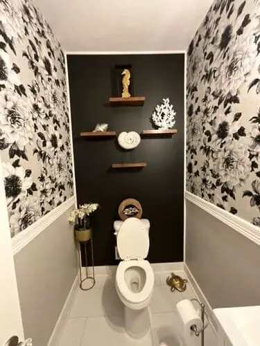 Long narrow bathroom with eclectic glam decor, featuring bold patterned wallpaper and a black accent wall behind the toilet for dramatic contrast.