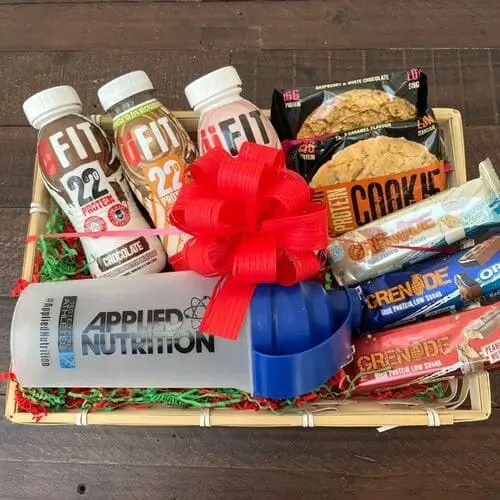 Gym junkie Christmas gift basket for men with gifts such as jump rope for cardio, shaker cups, protein cookies, protein shakes and bars