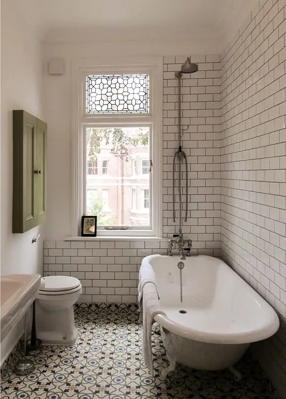 Narrow bathroom with glossy subway tiles and large mirror reflecting natural light for a spacious feel.