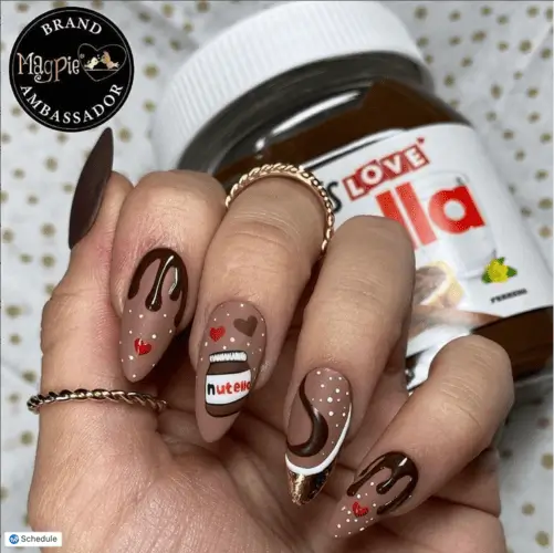 Nutella-inspired nails featuring chocolate brown base with Nutella jar nail art, chocolatey French tip drips, hearts, and chocolate swirl details for a sweet and trendy manicure.