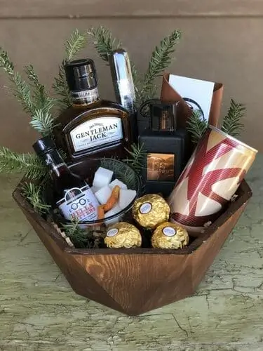 Whiskey lover's gift basket with whiskey glasses, ice molds, whiskey stones, a decanter set, bitters, sweet chocolate treats, and more. You can easily DIY this for Christmas!