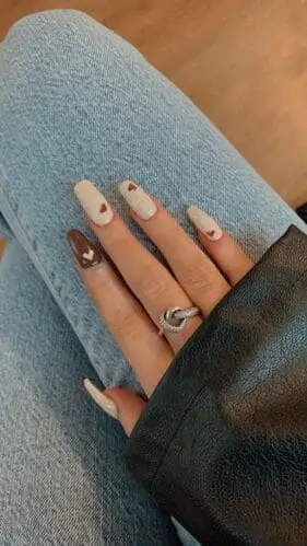 Trendy white nails with brown heart designs and brown accent nails—stylish and romantic nail art inspiration for a unique, earthy manicure.