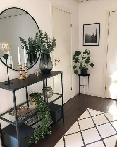 Stylish apartment entryway with a decorative console table, round mirror, and a tray for keys and mail. The space features a small plant and a cozy rug, creating a warm and inviting first impression for your home.