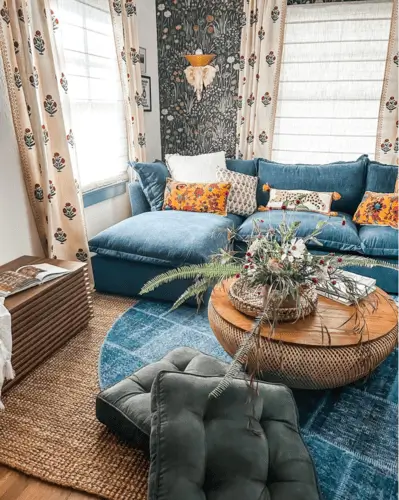 Maximalist blue living room with layered textures, bold patterns, and mismatched furnishings. Rich blue walls anchor the space while eclectic decor pieces create a playful, artistic atmosphere.