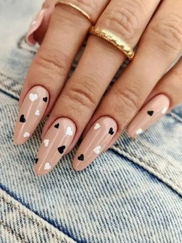 Nude Valentine’s nails with dainty black and white hearts for a minimalist and chic romantic manicure.