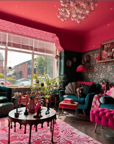 Bright raspberry pink and teal maximalist living room with dripping coffee table, bright velvet pink couch, and velvet teal accent chairs